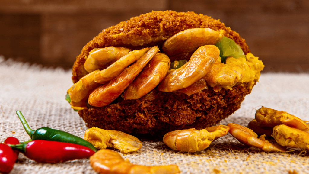 An acarajé, a traditional Brazilian street food, a deep-fried ball of mashed beans stuffed with spicy shrimp, presented on a rustic background with peppers.