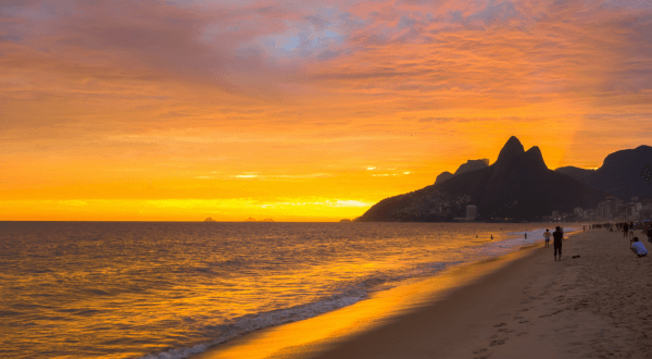 The sky above Ipanema Beach is painted with shades of purple and orange as the sun sets, creating a peaceful and picturesque end to the day at this popular Brazil beach destination.