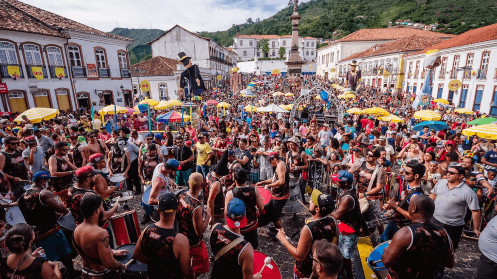 A festive crowd dancing in the streets of Ouro Preto, Brazil, with colonial architecture in the background during carnival.