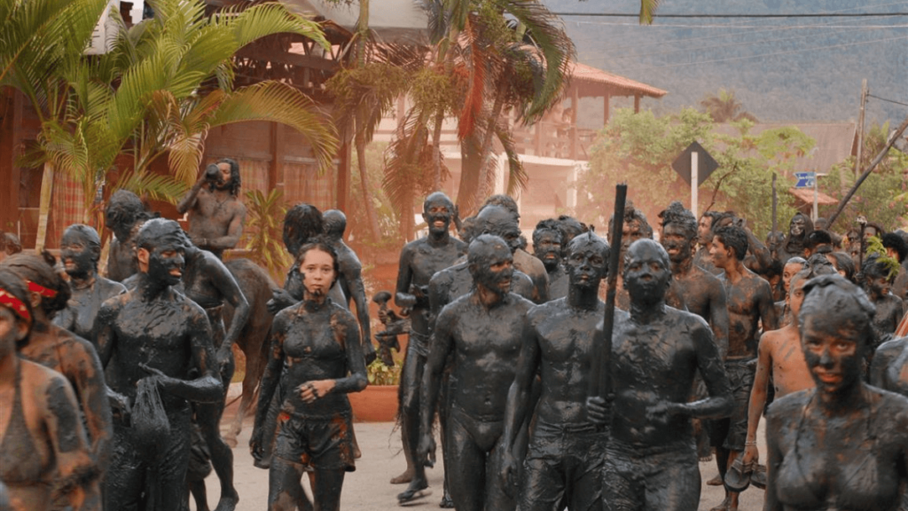 Participants covered in black mud, marching through the streets in a unique carnival tradition in Paraty, Brazil.