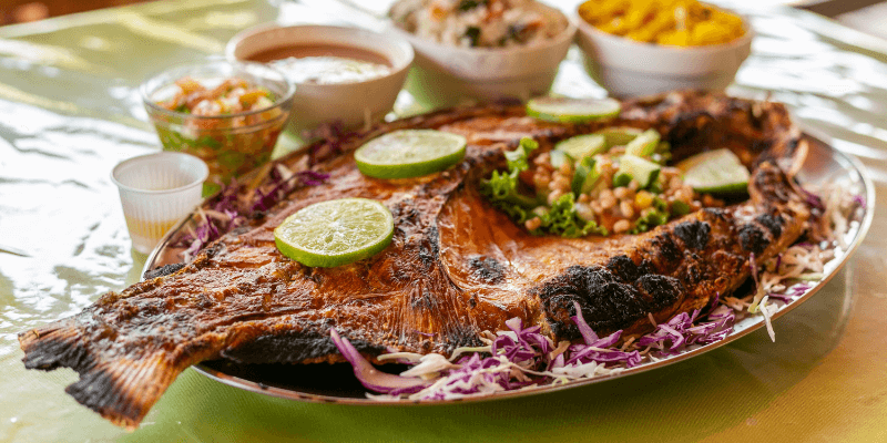 A traditional Amazonian dish featuring a grilled Tambaqui fish, garnished with lime and accompanied by bowls of side dishes, ready for a flavorful meal.