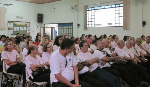 A group of attendees seated in white attire at a Spiritist center in Brazil, attentively participating in a spiritual lecture, reflecting the contemplative nature of Brazilian Spiritism.
