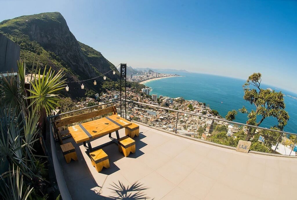 An outdoor seating area at Bar da Laje in Vidigal, Rio de Janeiro, offering breathtaking views of the city’s coastline and the Atlantic Ocean. Perfect for relaxing and enjoying the sunset.