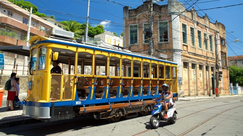 A charming yellow tram passing through the historic streets of Santa Teresa in Rio de Janeiro, with colonial-style buildings and vibrant street life. A top cultural attraction in the city.